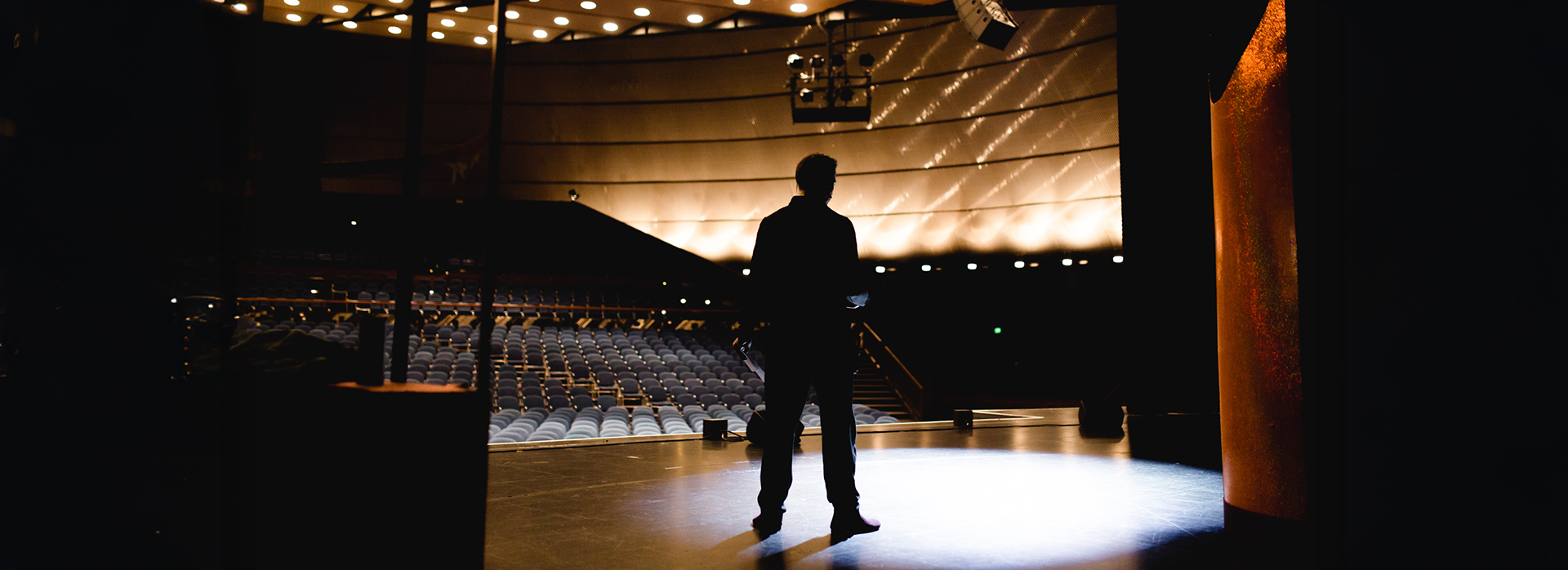 Soundcheck und Bühnenlicht bei Theater Liberi Silhouette eines Darstellers bei der Bühnenprobe im leeren Zuschauerraum – die Bühne ist in stimmungsvolles Licht getaucht.