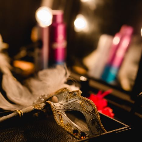 theater-liberi-maske-schminktisch-schminke-kulisse.jpg Detailaufnahme eines Schminktischs mit venezianischer Maske, Spiegellichtern und unscharfem Hintergrund.