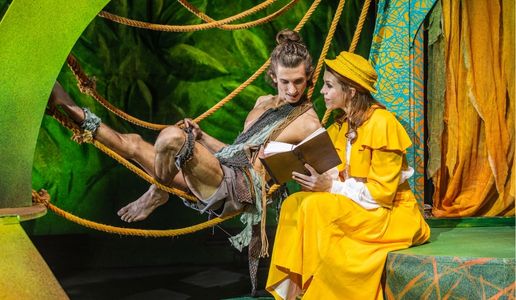 Tarzan und Jane in einer Szene aus „Tarzan – das Musical“ von Theater Liberi Tarzan liegt in Lianen, während er gemeinsam mit Jane ein Buch liest – Szene aus „Tarzan – das Musical“ von Theater Liberi
