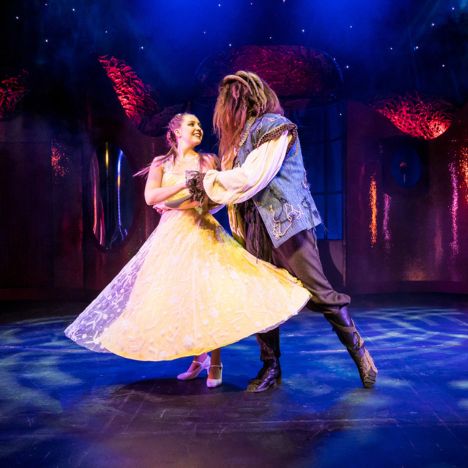 theater-liberi-die-schoene-und-das-biest-tanzszene.jpg Belle und das Biest tanzen gemeinsam auf der Bühne unter romantischer Beleuchtung.