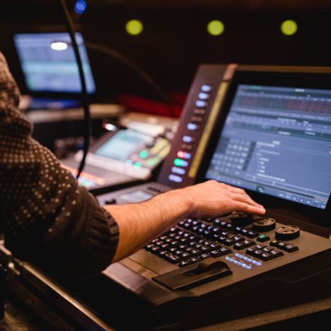 theater-liberi-technikpult-ton-lichtsteuerung-backstage.jpg Hand eines Technikers an einem modernen Licht- und Tonpult im Theater mit geöffneten Steuerungsprogrammen.
